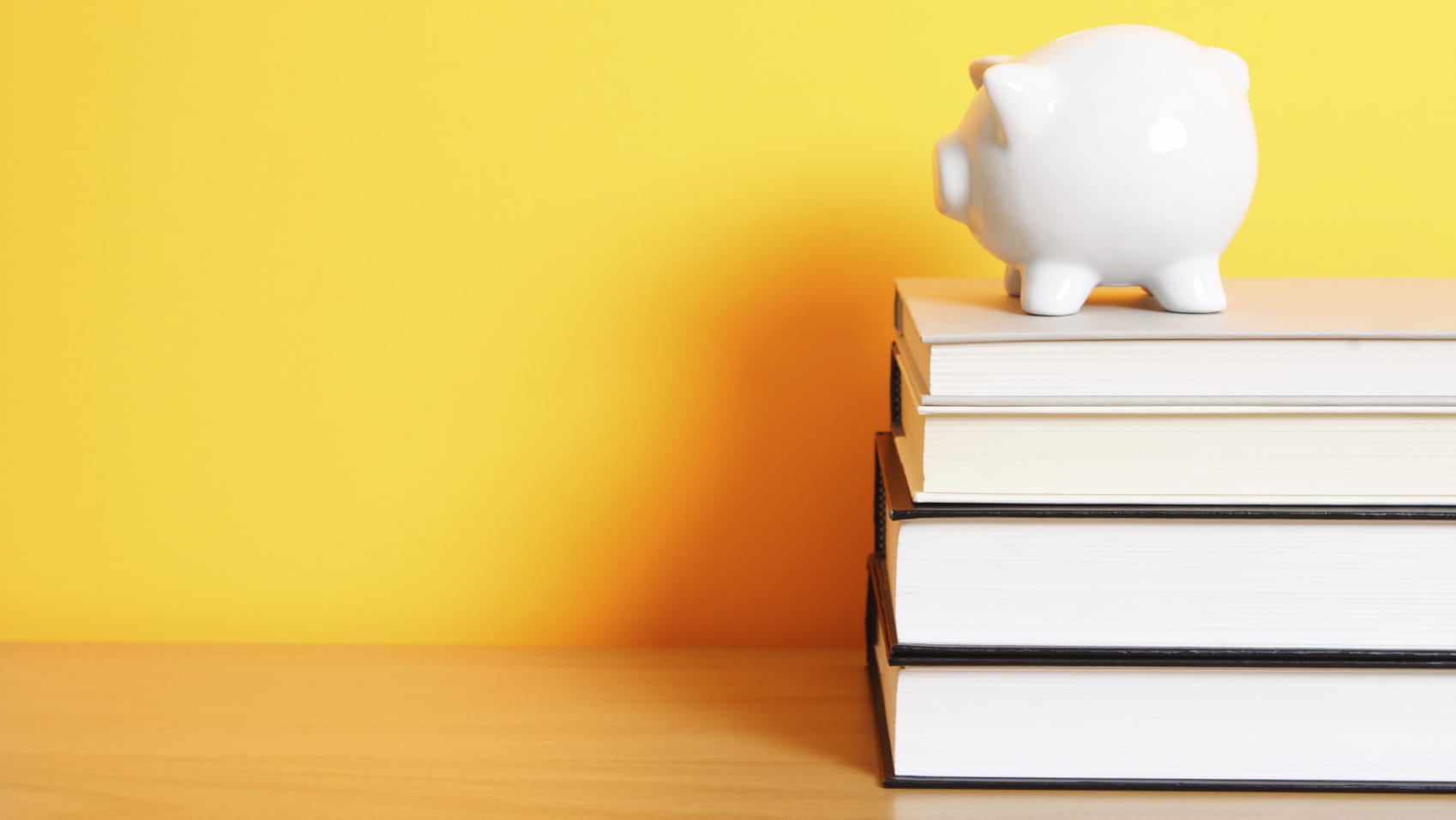 Piggy bank on books with yellow background